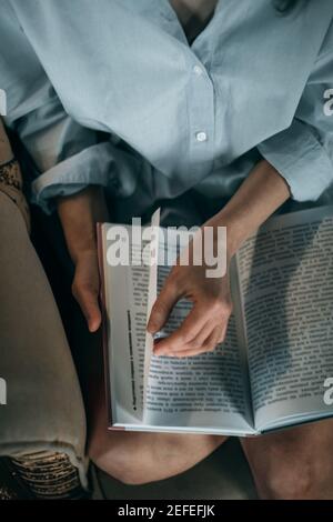 Primo piano su mano donna che gira pagina nel libro. Donna ha letto un libro. Vista dall'alto Foto Stock