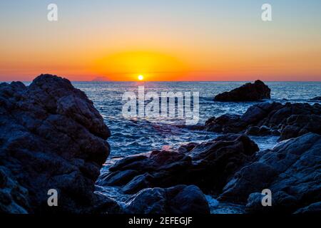 Tramonto sulla costa rocciosa. Tramonto sul Mar Tirreno in Calabria, Italia. Foto Stock