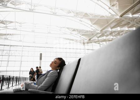 Profilo laterale di una donna d'affari che dorme in un aeroporto Foto Stock