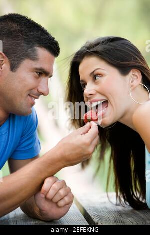 Primo piano di un uomo medio adulto che alimenta una giovane donna una fragola Foto Stock