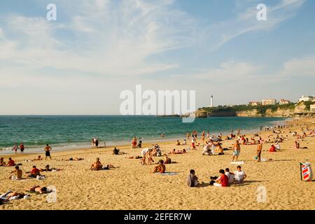 Turisti in spiaggia, Grande Plage, Phare de Biarritz, Biarritz, Francia Foto Stock