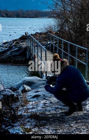 Fotografo al lavoro sulla riva del lago di Costanza. Inverno con ghiaccio. Vereistem Ufer lockt zum Fotografieren. Ingeborg Kuhn an der Arbeit Foto Stock