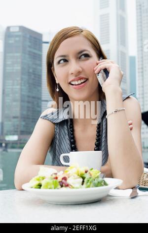 Giovane donna che parla su un telefono cellulare a un marciapiede caffè Foto Stock