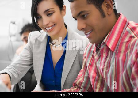 Close up di un uomo d'affari che guarda un notebook con un donna d'affari e sorridente Foto Stock