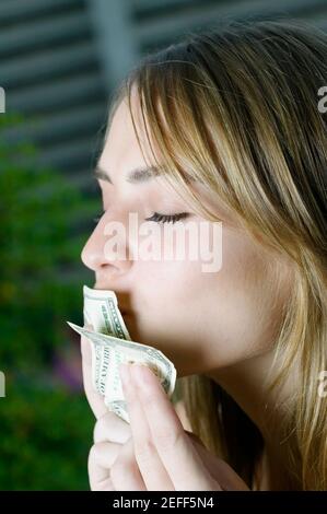 Primo piano di una giovane donna che bacia le fatture del dollaro americano Foto Stock