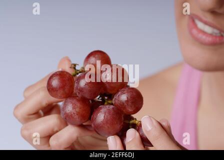 Close-up di una giovane donna tenendo un grappolo di uva rossa Foto Stock