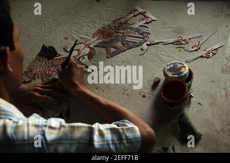 L'artigiano colora un burattino wayang kulit nel negozio di artigianato Balai Agung a Surakarta, Giava Centrale, Indonesia. Il tradizionale teatro delle ombre dei burattini conosciuto come wayang kulit è diffuso sulle isole di Giava e Bali in Indonesia. I burattini per wayang kulit sono realizzati in pelle di bufalo. La produzione di un burattino richiede circa sei giorni. Ogni personaggio ha le proprie caratteristiche e può essere facilmente identificato dagli spettatori. Foto Stock