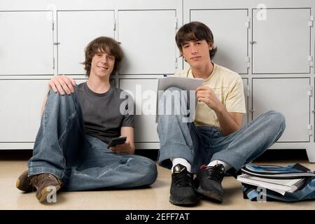 Ritratto di due studenti delle scuole superiori seduti di fronte armadietti Foto Stock