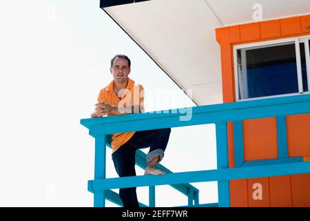 Ritratto di un adulto medio appoggiato alla ringhiera di una capanna di bagnino Foto Stock