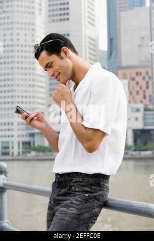 Profilo laterale di un mid adult uomo messaggi di testo e. sorridente Foto Stock