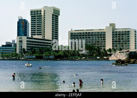 Vista laterale di edifici commerciali con un lago in primo piano, San Juan, Puerto Rico Foto Stock