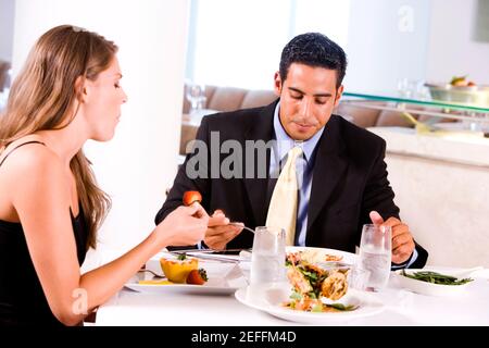 Profilo laterale di una giovane donna e di un mid adult uomo che mangia in un ristorante Foto Stock