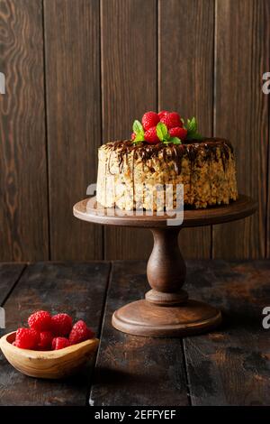 Torta Anthill decorato con lamponi, cioccolato e noci su vecchio tavolo di legno. Messa a fuoco selettiva. Foto Stock