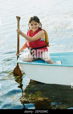 Ritratto di una ragazza che canottava una barca in un lago e sorridendo Foto Stock