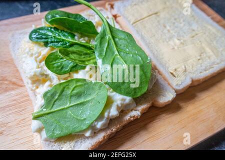 Preparare un sandwich di maionese all'uovo con foglie di spinaci per il pranzo. Foto Stock