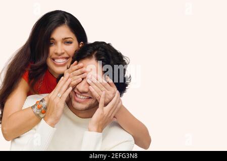 Ritratto di una giovane donna che copre gli occhi di un giovane uomo da dietro Foto Stock