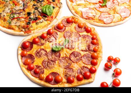 diverse pizze di vario tipo in assortimento con basilico verde, funghi, pomodori, formaggio, pepe per menu. Primo piano. Fast food o pizza party dinn Foto Stock