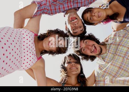 Basso angolo vista di tre giovani donne e due giovani uomini in un huddle Foto Stock