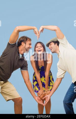 Metà uomo adulto e un giovane uomo che fa a forma di cuore di fronte a una giovane donna Foto Stock