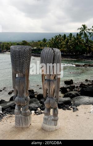 Statue di torcia tiki sulla spiaggia, Città del Rifugio, Costa di Kona, Parco storico Nazionale Puuhonua o Honaunau, Big Island, Isole Hawaii, Stati Uniti Foto Stock
