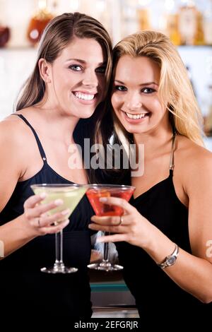 Ritratto di due giovani donne che tostano Martini in un bar Foto Stock