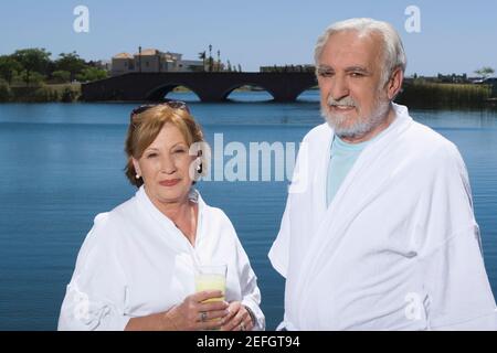 Donna anziana che tiene un bicchiere di succo e sta con un uomo anziano Foto Stock
