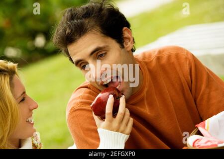 Primo piano di una giovane donna che alimenta una mela ad un uomo adulto medio Foto Stock