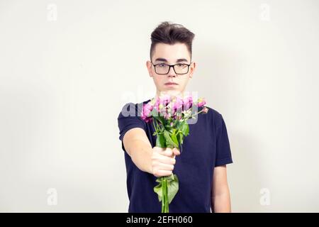 un giovane serio in calici tiene fuori un bouquet di fiori non freschi. concetto di separazione Foto Stock
