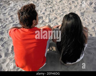 Vista ad alto angolo di una giovane coppia seduta sul spiaggia Foto Stock