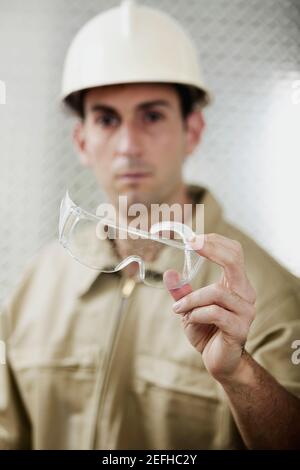 Ritratto di un uomo medio adulto che tiene gli occhiali protettivi Foto Stock