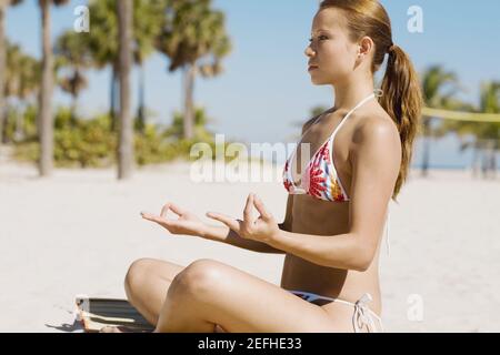 Profilo laterale di una giovane donna meditando sulla spiaggia Foto Stock