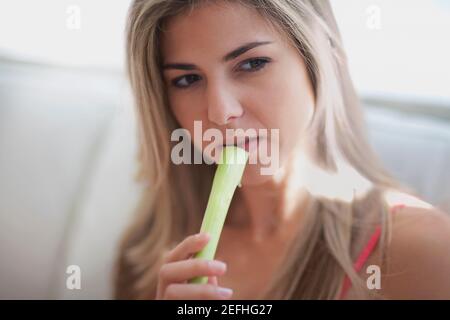 Primo piano di una donna mid adulta che mangia sedano Foto Stock