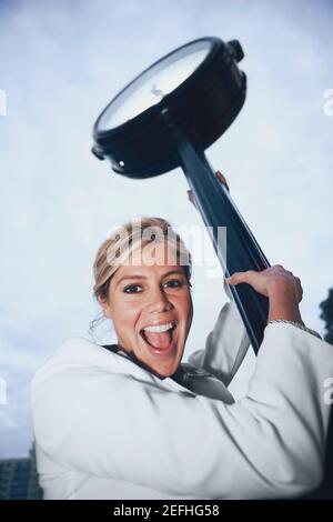 Ritratto di una donna d'affari che tiene il palo di un orologio e. urla Foto Stock