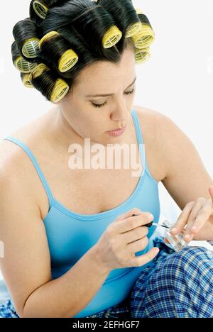 Donna matura che applica smalto per unghie sulle sue unghie Foto Stock