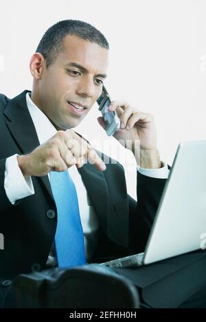 Close up di un uomo d'affari che parla su un telefono cellulare e. utilizzando un computer portatile Foto Stock