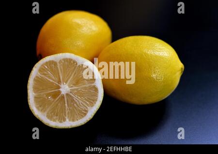 3 limoni, due interi e mezzo su sfondo nero. Sottoesposizione intenzionale Foto Stock