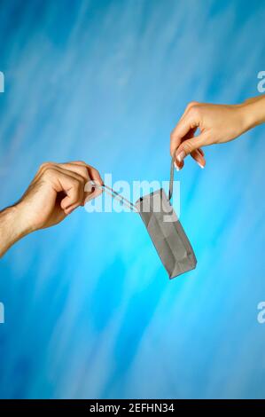 Primo piano di un uomo e di un womanÅ½s mani che tengono un borsa per la spesa Foto Stock