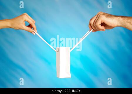 Primo piano di un uomo e di un womanÅ½s mani che tengono un borsa per la spesa Foto Stock