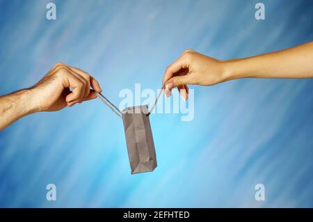 Primo piano di un uomo e di un womanÅ½s mani che tengono un borsa per la spesa Foto Stock