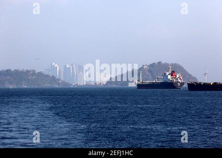 Navi in attesa nell'Oceano Pacifico per entrare nel canale di Panama, i grattacieli di Panama City sullo sfondo, Panama Foto Stock