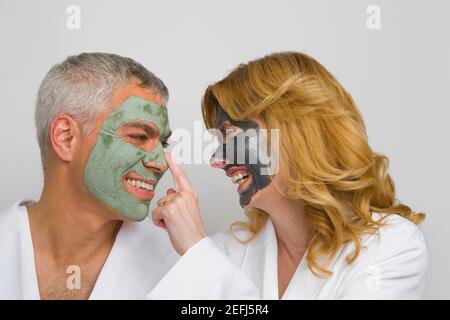 Primo piano di una coppia matura che indossa maschere facciali e sorride Foto Stock