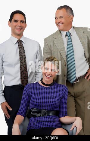 Close up di una donna d'affari che sorride con due uomini d'affari in piedi dietro lei Foto Stock