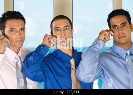 Ritratto di tre uomini d'affari che parlano su telefoni cellulari Foto Stock