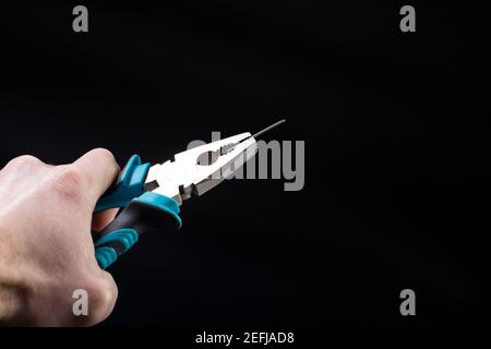 Estrarre un chiodo da uno pneumatico per auto, utilizzando delle pinze su sfondo nero. Foto Stock