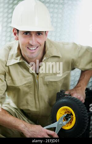 Ritratto di un uomo medio adulto che stringe un dado di una ruota Foto Stock