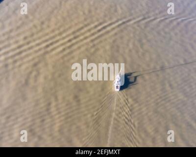 Vista aerea di un piccolo motoscafo turistico che naviga nelle acque verdi del fiume Tago vicino al porto di Lisbona Marina, Lisbona, Portogallo. Foto Stock