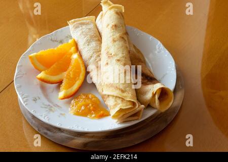 Crepes con marmellata d'arancia e arance - sfondo di legno Foto Stock