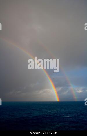 Il doppio arcobaleno appare sull'Oceano Pacifico al crepuscolo a Big Island Hawaii USA. Foto Stock