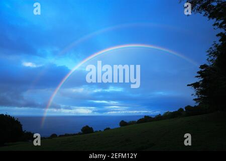 Il doppio arcobaleno appare sopra l'Oceano Pacifico nel crepuscolo Hawaii USA. Foto Stock