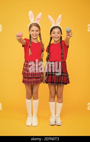 per voi. inizia la caccia alle uova. vacanza primaverile tradizionale. buona pasqua. la primavera è in arrivo. concetto di infanzia felice. ragazze piccole bunny spighe sfondo giallo. bambini simpatici sorella piccola celebrare pasqua. Foto Stock